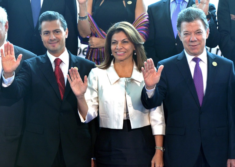 Mexican President Enrique Pena Nieto (L), Costa Rican President Laura Chinchilla and Colombian President Juan Manuel Santos wave during the family photo of the XXIII Ibero-American Summit, in Playa Bonita Hotel, 30 km from Panama City, on October 19, 2013. Many Latin American leaders were no-shows at the opening of the summit, revealing the foundering direction of the annual forum. The event was to run through Saturday in Panama City, with a dozen or so leaders from Spain, Portugal and their former colonies in the Americas set to discuss major reforms to the organization. AFP PHOTO / Rodrigo ARANGUA