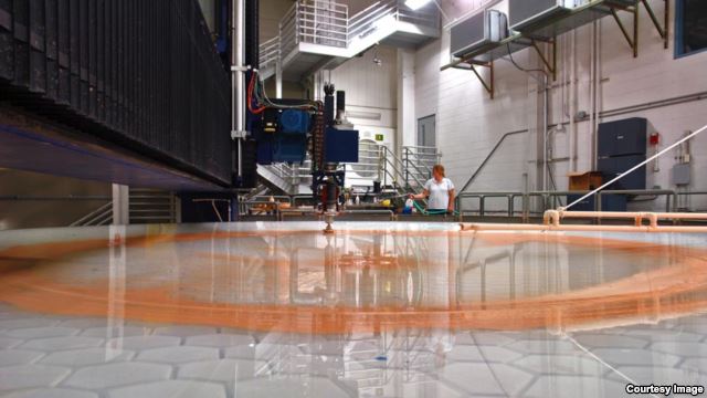 Scientists use a series of fine abrasives to polish the mirror to a precise prescription. Specialist Leslie Utley monitors the operation. (Giant Magellan Telescope–GMTO Corporation)