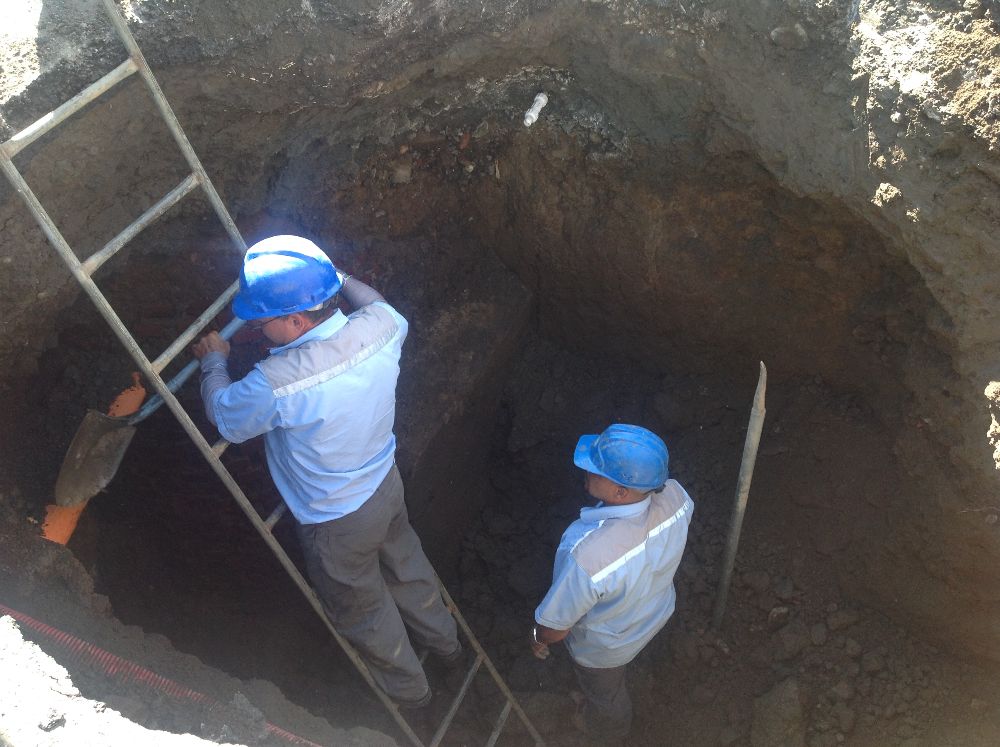 Workers inspect the hole which appeared in the middle of the roadway in Barrio Cuba. (Photo courtesy of CRHoy.com)