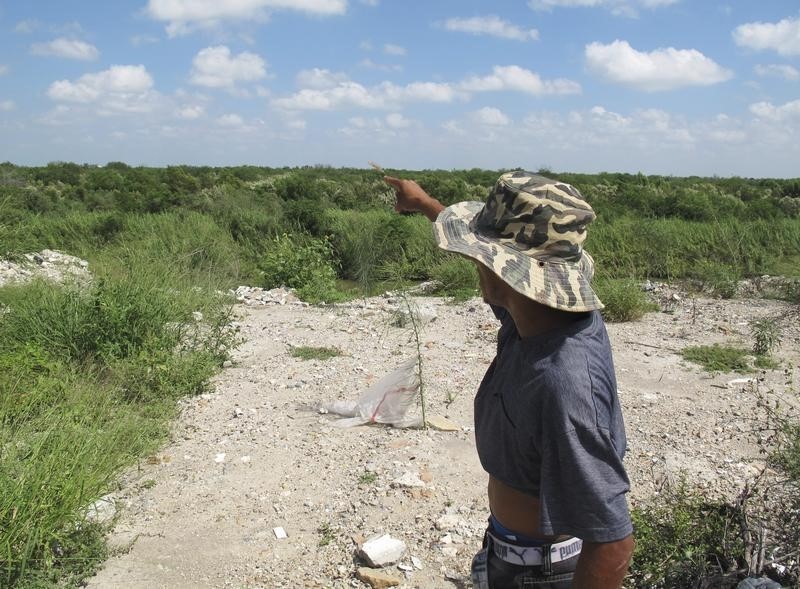 Honduran migrant Juan Marcos Guardado points to the United States across the Rio Grande (Rio Bravo), the border between Mexico and the U.S., as he speaks to Reuters in Reynosa October 2, 2014. Tens of thousands of Central American migrants are being kidnapped, abused and extorted by Mexican gangs just yards from the United States in a growing racket that may be worth up to $250 million (155.61 million pounds) a year. Guardado, a 27-year-old roofer, said he was betrayed by a fellow Honduran shortly after arriving by bus in Reynosa. The man handed Guardado over to men who said they were members of the feared Gulf Cartel and extorted $1,500 from his relatives. They then passed him onto another kidnapping group. The kidnapping of Central American migrants, some of the poorest people in the Americas, is not new. But a recent surge in the number of Central American migrants heading for the United States - coupled with successful operations by Mexican security forces to disrupt cartels' drug business - has turned a former sideline into an increasingly important revenue stream for rank and file cartel members. To match Insight USA-IMMIGRATION/KIDNAPPING Picture taken October 2, 2014. REUTERS/Simon Gardner